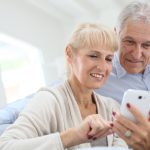 Senior couple at home using smartphone