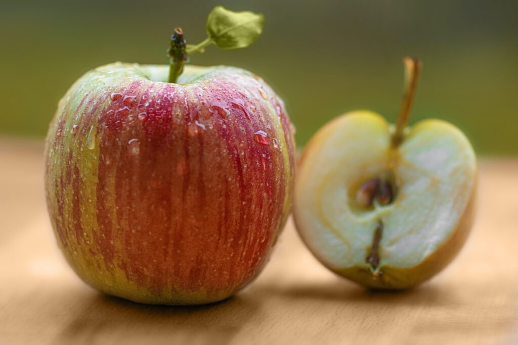 Das Foto zeigt einen ganzen udn einen angeschnittenen Apfel